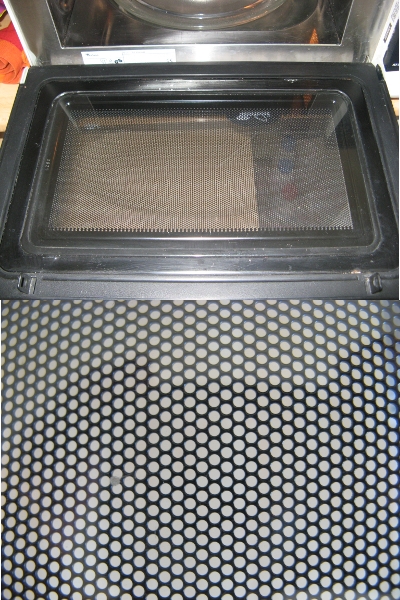 Porte d'un four micro-ondes et gros plan sur les trous du grillage interne