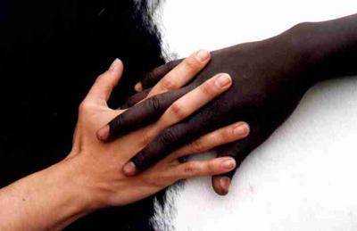 Un main blanche et une main noir entremêlées par les doigts